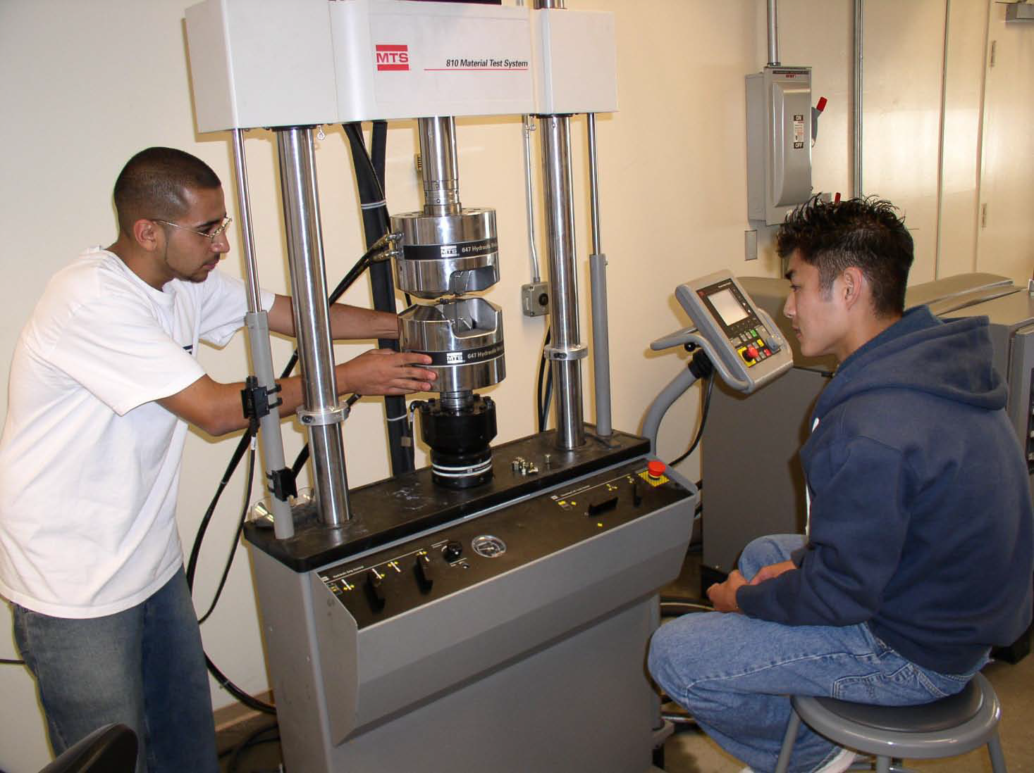 Two students working with a amchine in the structures lab 